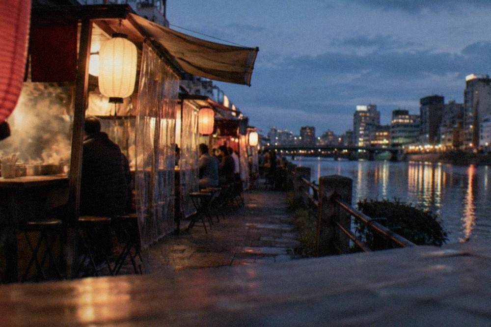 Evening view across the Naka River with illuminated yatai stalls along the Nakasu embankment