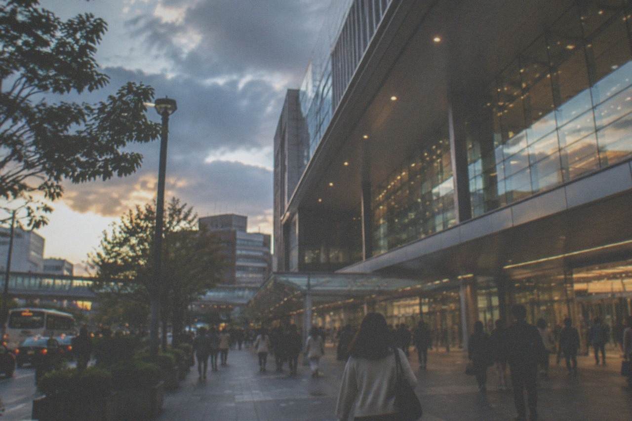 Hakata Station exterior with travellers walking past the glass entrance at dusk