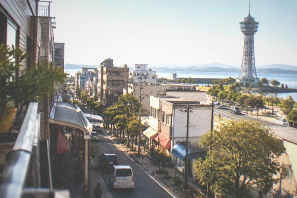 A tall seaside observation tower standing above a waterfront park under a clear sky