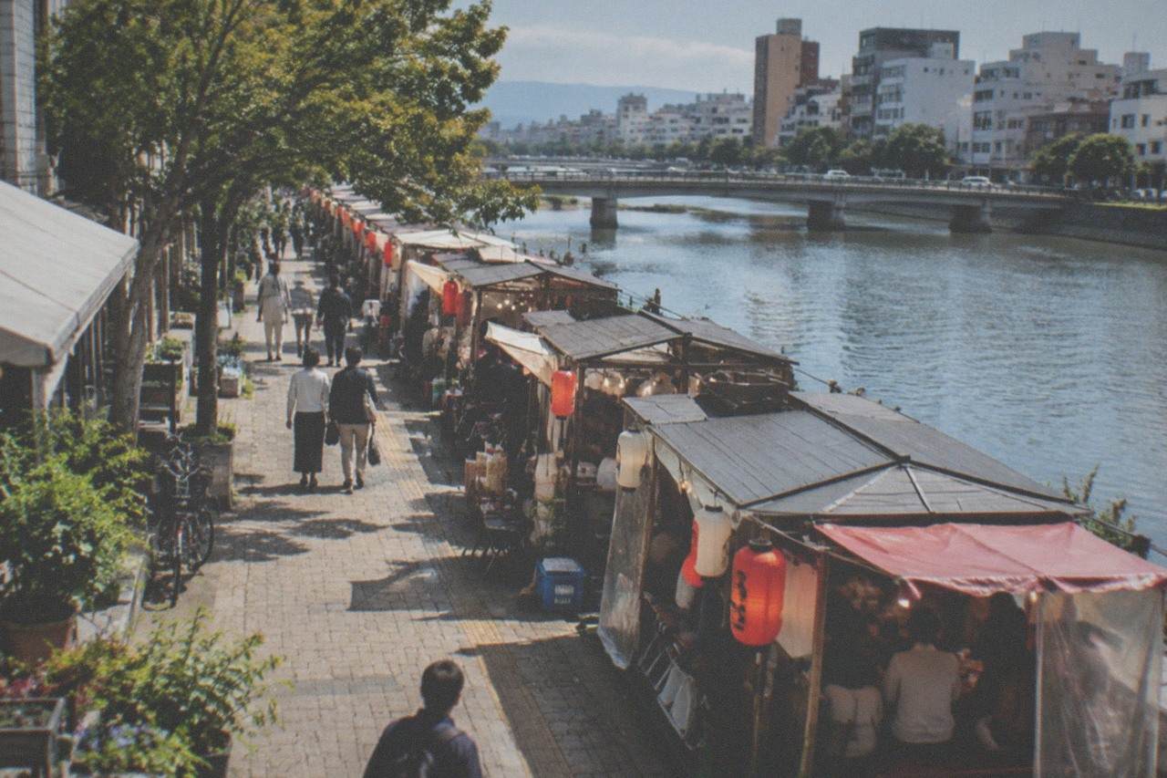 Illuminated food stalls lined along a river at night in a Japanese city