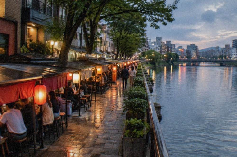 Illuminated food stalls lining a riverside street at night with lanterns and customers seated at counters