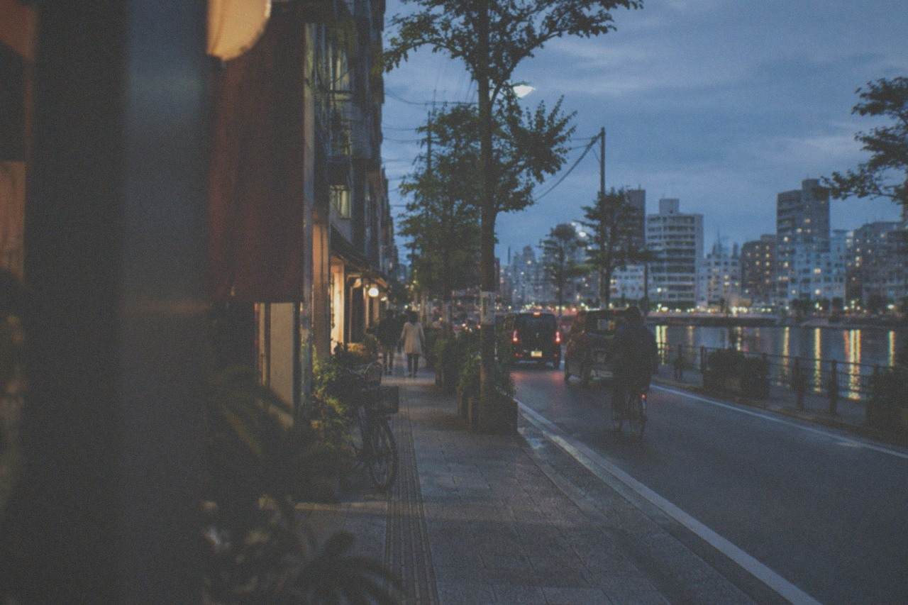 Night view over a Japanese city skyline with illuminated high-rise buildings and a river reflecting the lights