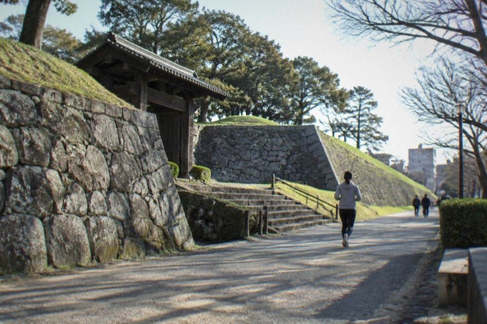 Stone walls and green lawns of the Fukuoka Castle ruins in Maizuru Park under a clear sky