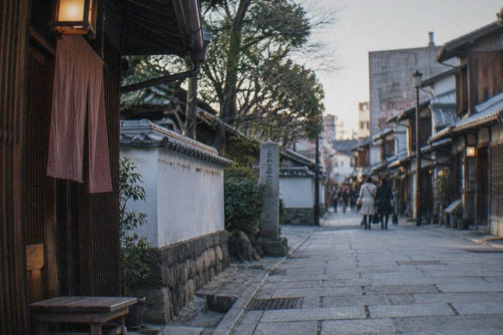 A quiet stone-paved lane in Hakata old town with traditional wooden machiya facades under a soft evening sky