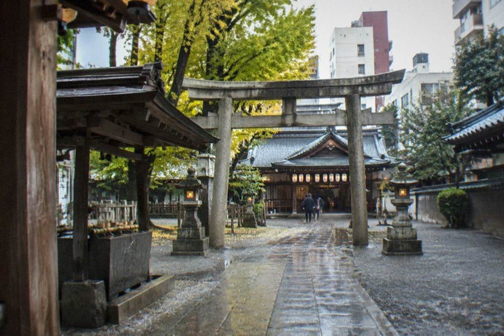 The stone torii gate and approach path of Kushida Shrine with lanterns hanging under the eaves