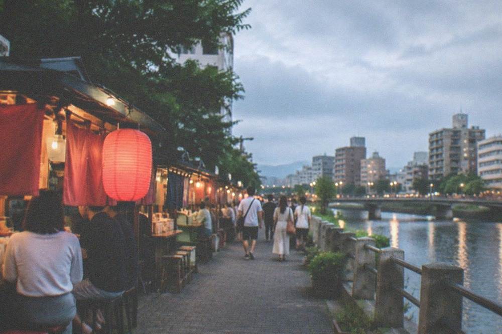 Illuminated food stalls along the Naka River on a warm Fukuoka summer evening