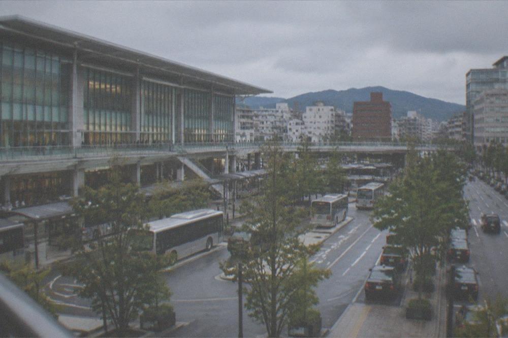 A limited express train at a platform in a regional Kyushu station with mountains beyond