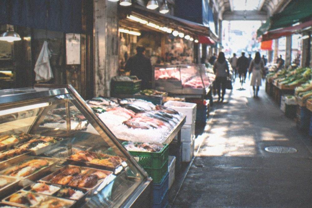 a glass display case filled with rows of prepared fish dishes and rice boxes