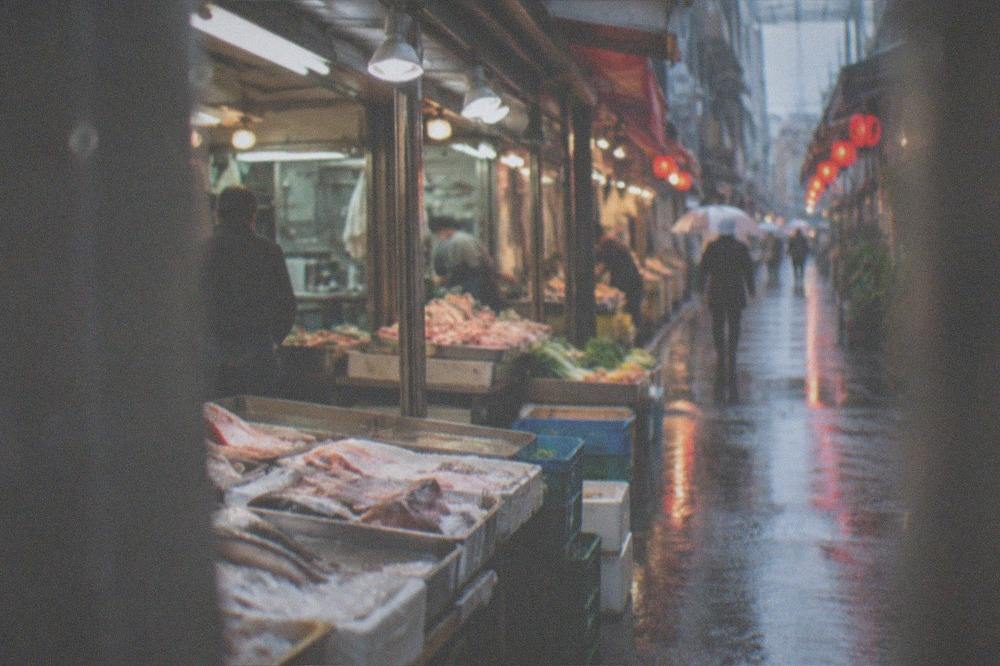 a rain slicked street at dusk with red lanterns reflecting in the wet pavement
