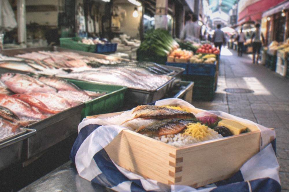 a packed wooden box of prepared fish and rice ready for travel with a cloth wrapper