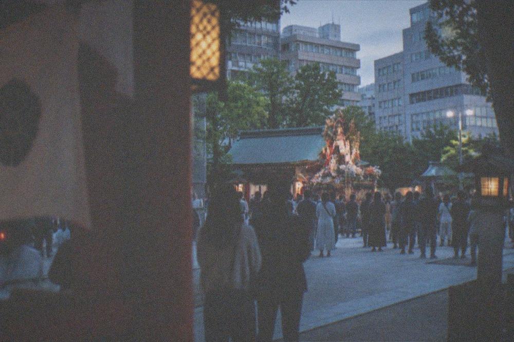 A decorated festival float standing in a shrine precinct surrounded by onlookers