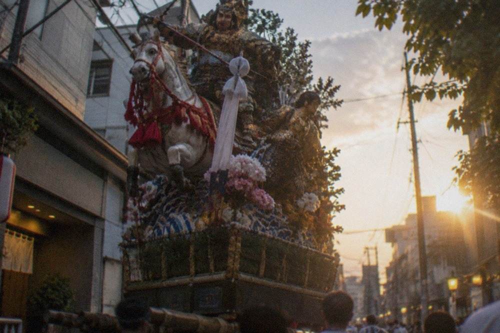 Lavishly decorated Yamakasa float with carved figures standing on a Hakata street at dusk