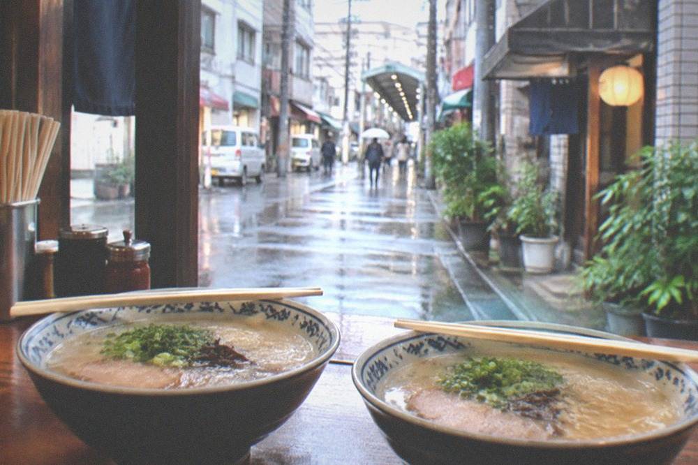 Two ramen bowls side by side on a restaurant counter with chopsticks resting on top