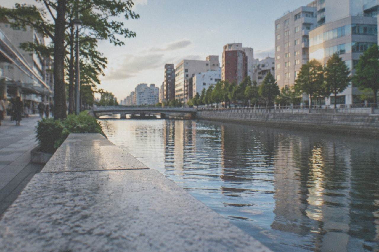 Illuminated high-rise buildings along a canal in central Fukuoka at dusk