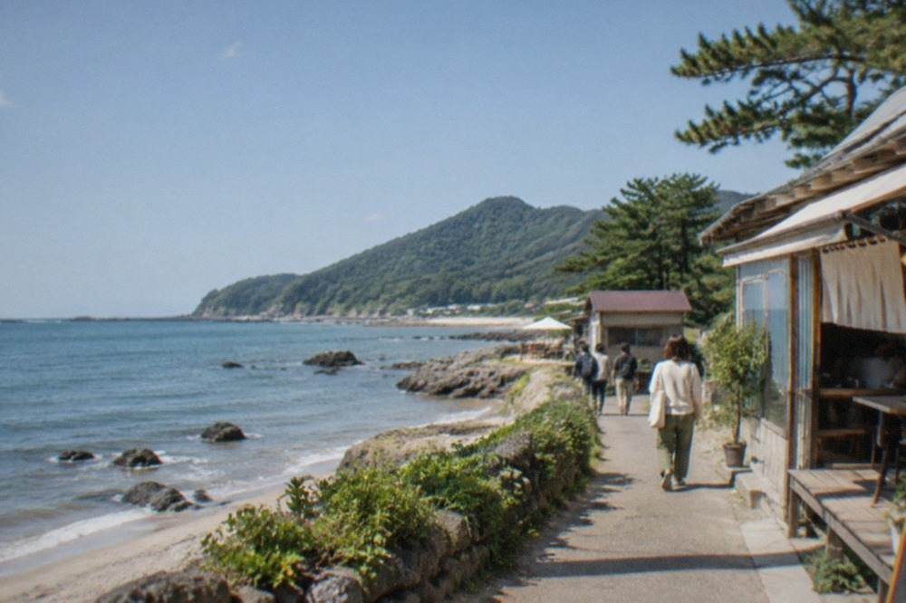 Rocky coastline with calm blue water and green pine-covered hills under a clear sky