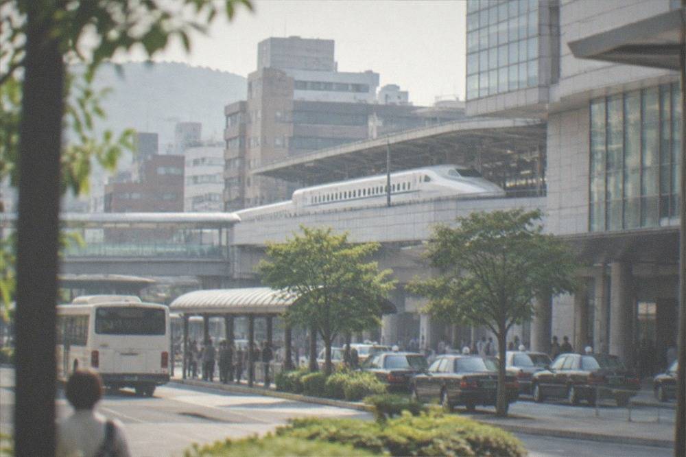 A white bullet train standing at a station platform beside a modern terminal building