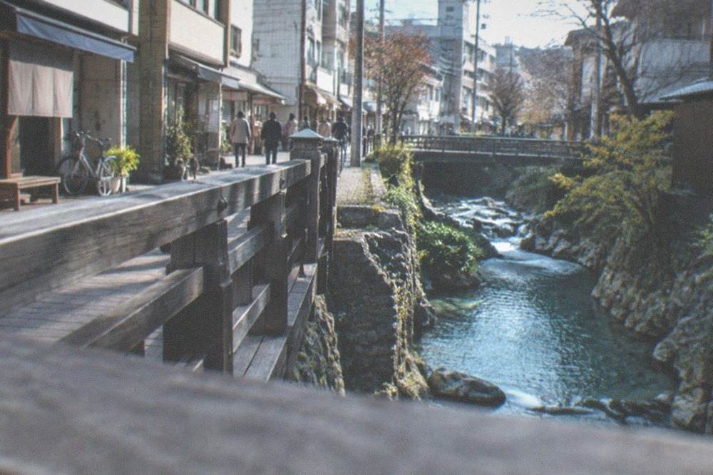 A wooden footbridge crossing a narrow rocky gorge with turquoise water below