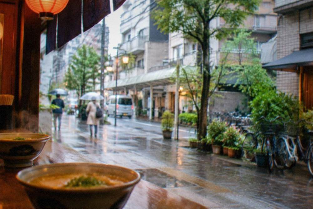 Steaming bowls of noodles on a wooden counter lit by warm lantern light