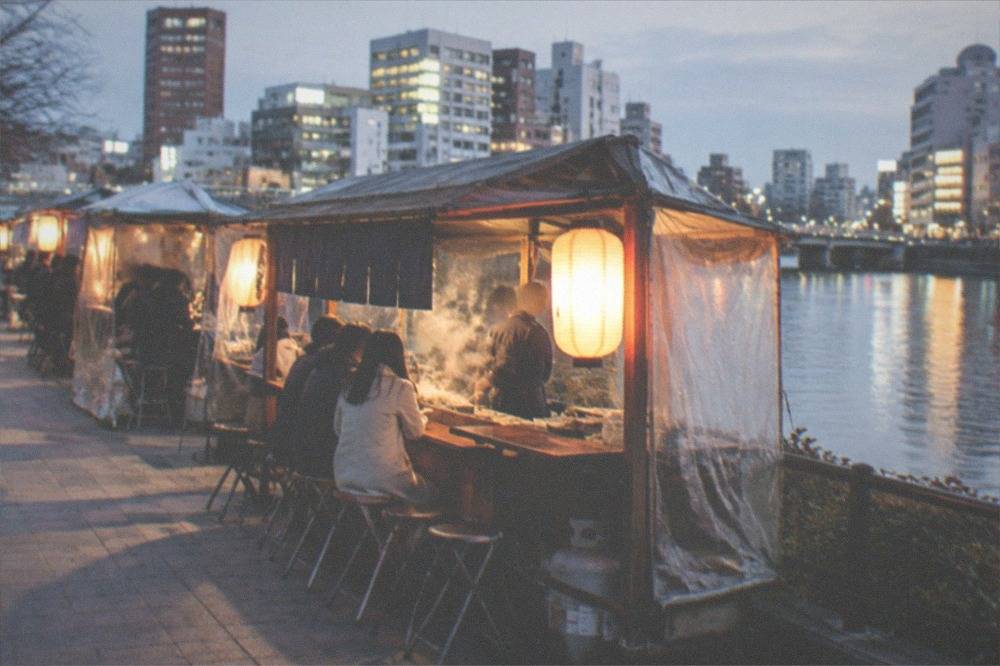 Illuminated yatai food stalls glowing along the Naka River at night in Nakasu