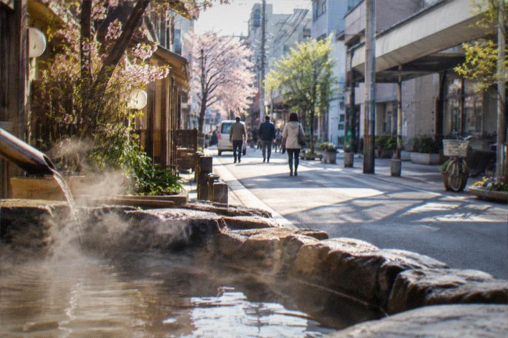 Steam rising from hot spring pools beside a small town street