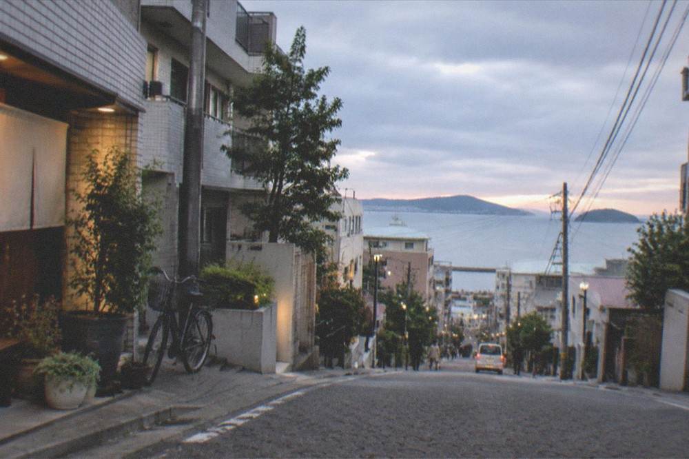 Wide view of a calm bay with islands on the horizon at dusk