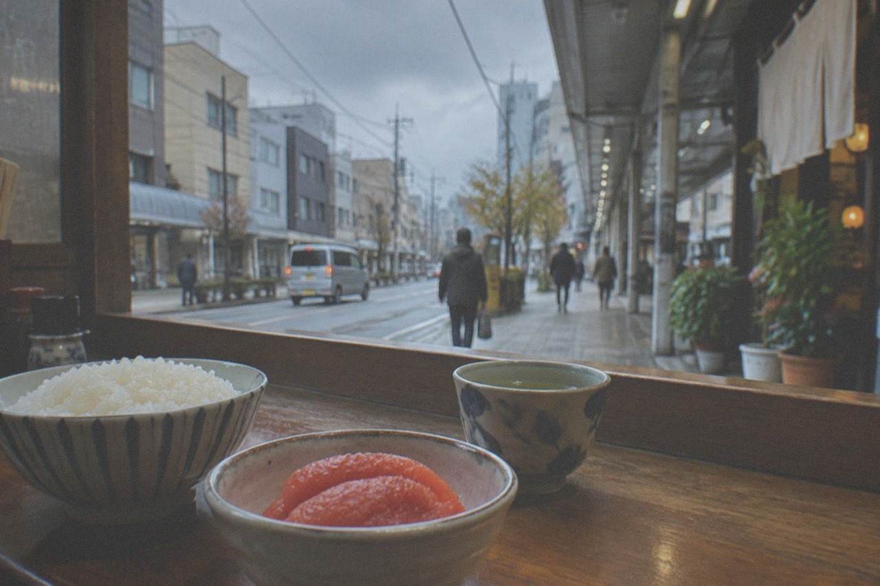 Bowl of bright red mentaiko roe beside rice and tea on a wooden counter