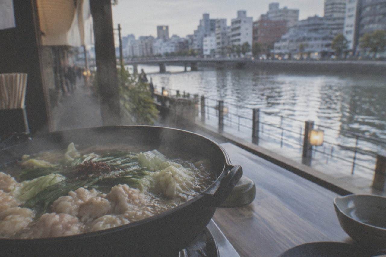 A steaming cast iron hot pot filled with offal, cabbage and broth on a restaurant table