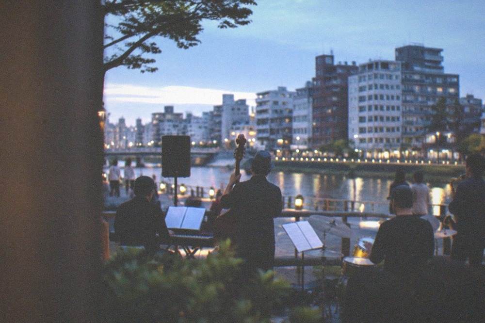 A jazz band performing on an outdoor stage in a city street at dusk
