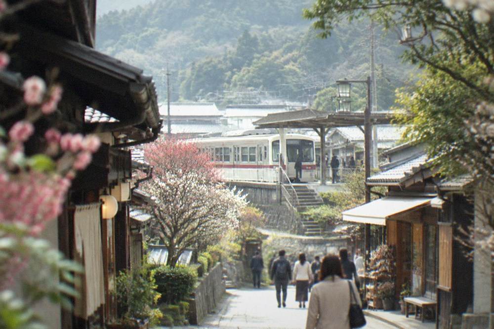 A two-car Dazaifu branch line train waiting at a small suburban station platform