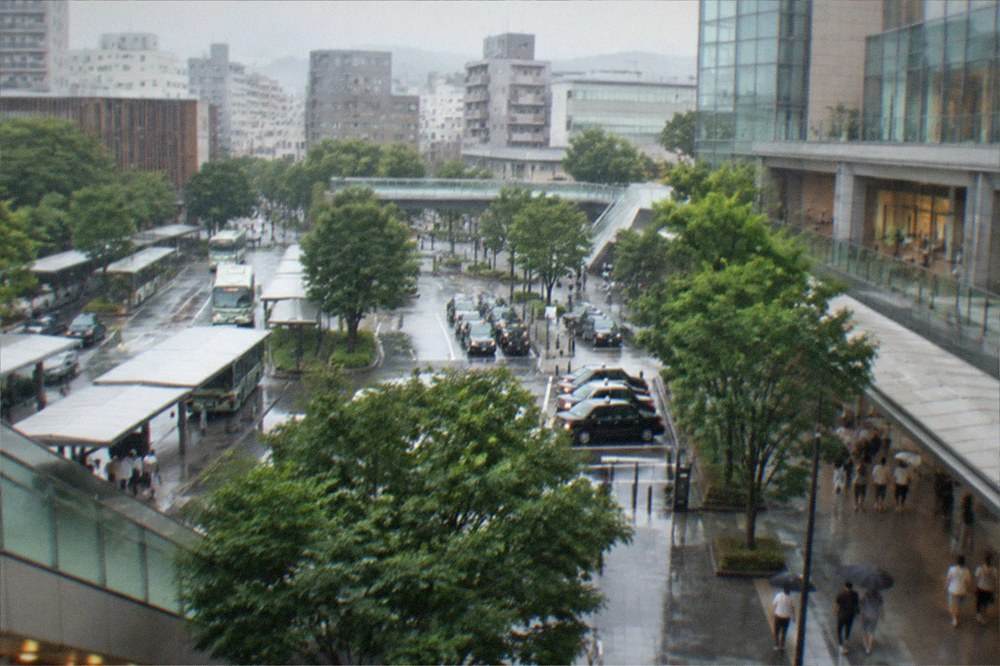 Rain slicked streets outside Hakata Station with commuters moving under cover
