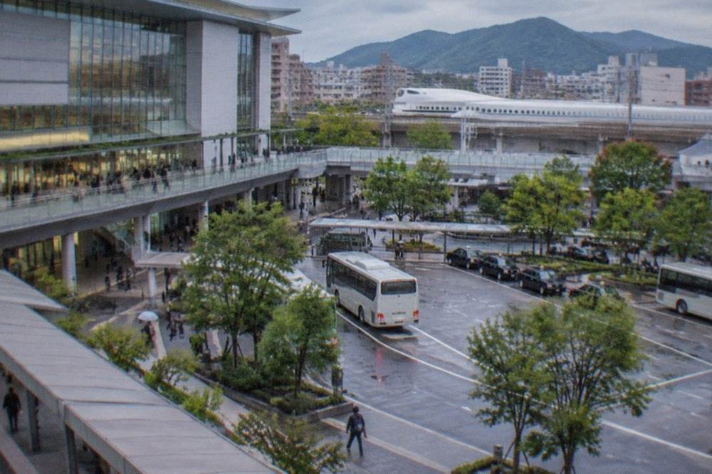 Shinkansen train at a station platform in Kyushu with mountains in the distance