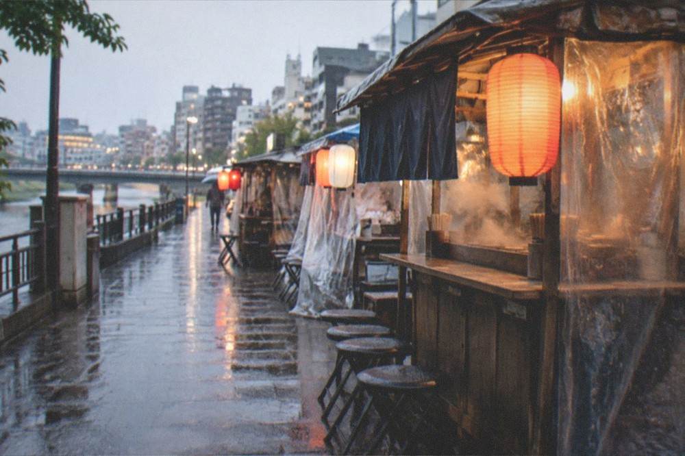 An empty street corner where food stalls stand shuttered in the rain