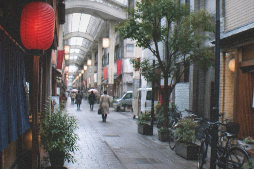 Historic shopping arcade street with lanterns and small shopfronts in the late afternoon
