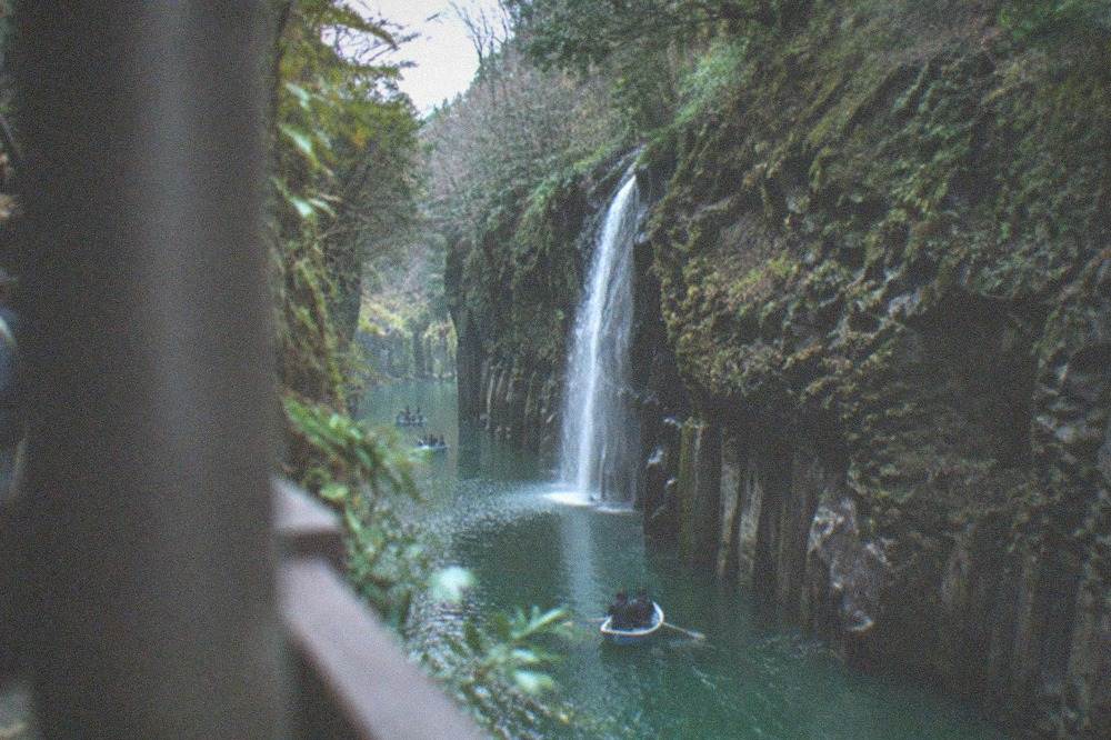 Takachiho Gorge with sheer cliffs and a boat on the green river below