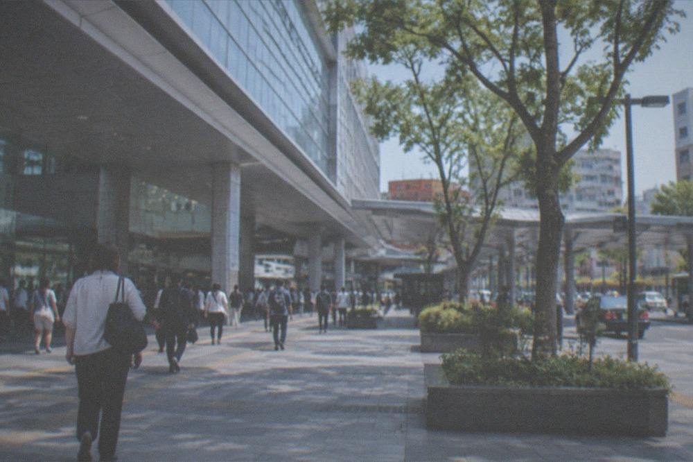Hakata Station concourse with travellers walking beneath departure signs