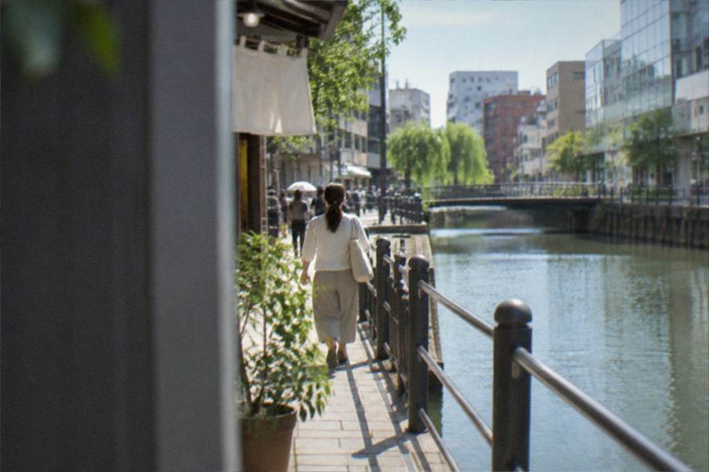 Canal waterway running between glass retail buildings lit by morning light