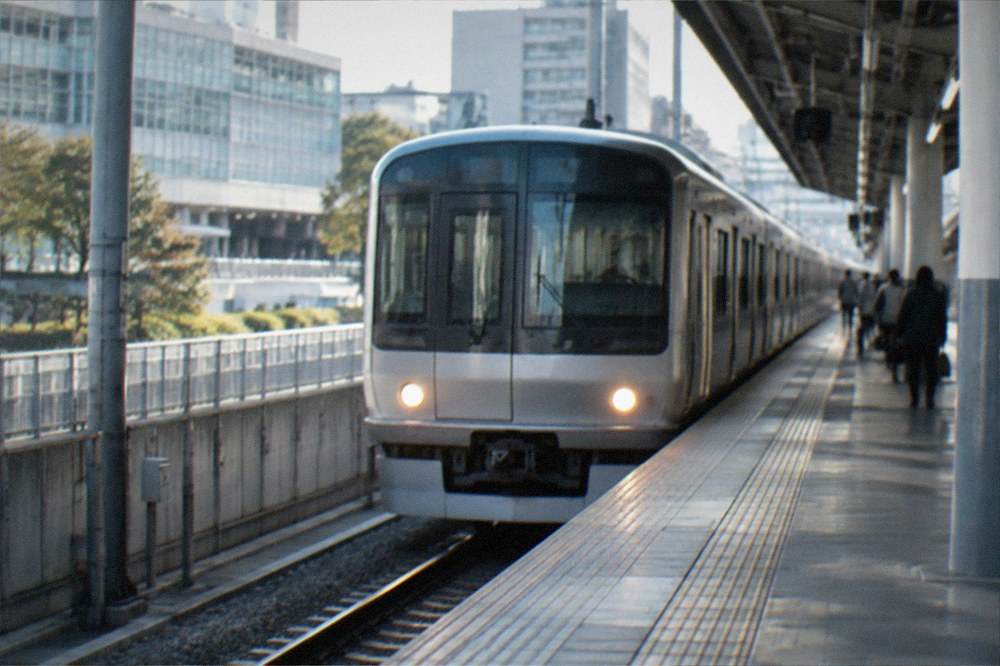 A clean subway platform with a train arriving at a station in Fukuoka