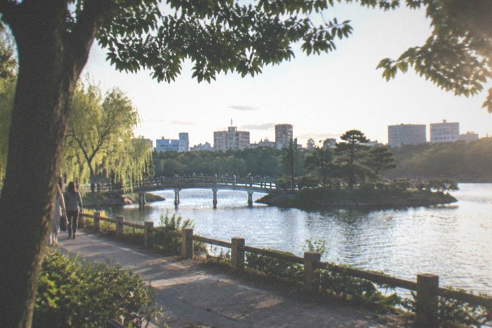 Ohori Park lake path with the traditional garden bridge and city skyline behind