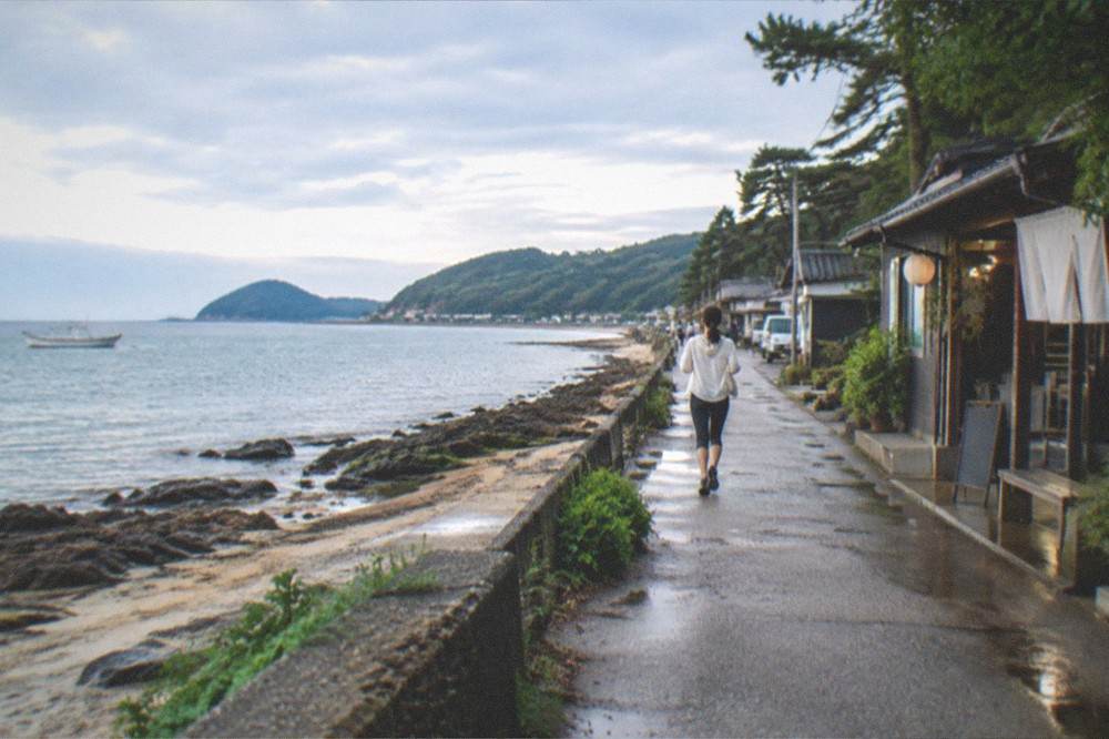 Itoshima peninsula coastline with a fishing boat and calm sea under a wide sky