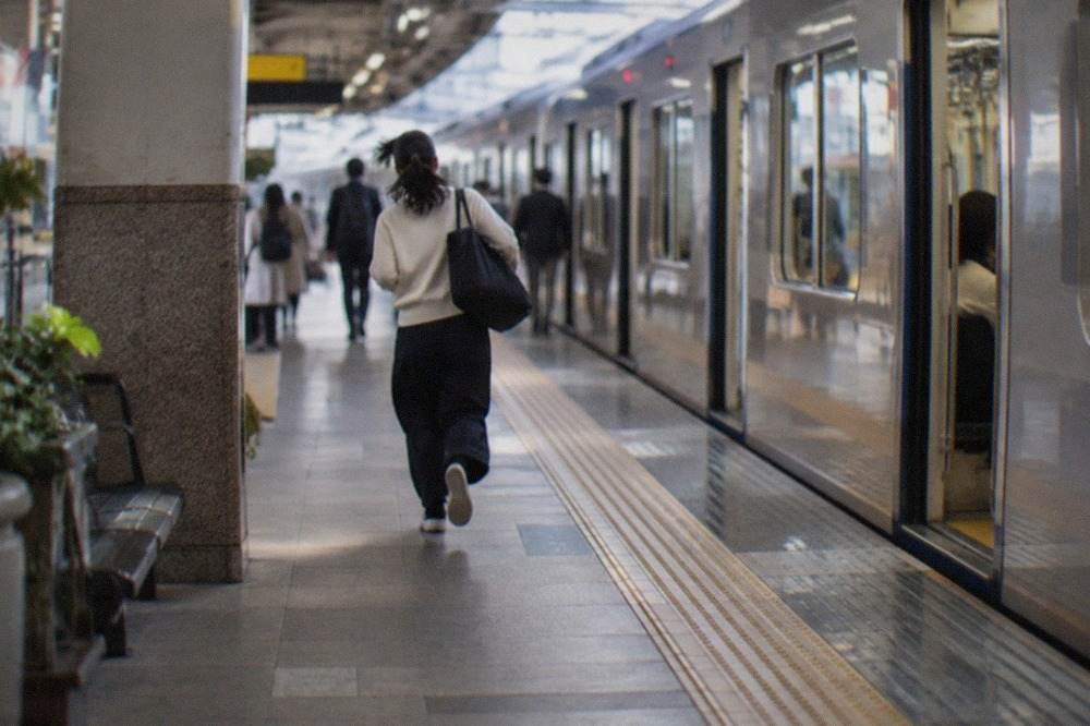 A subway platform at a Fukuoka City subway station with a train waiting at the doors