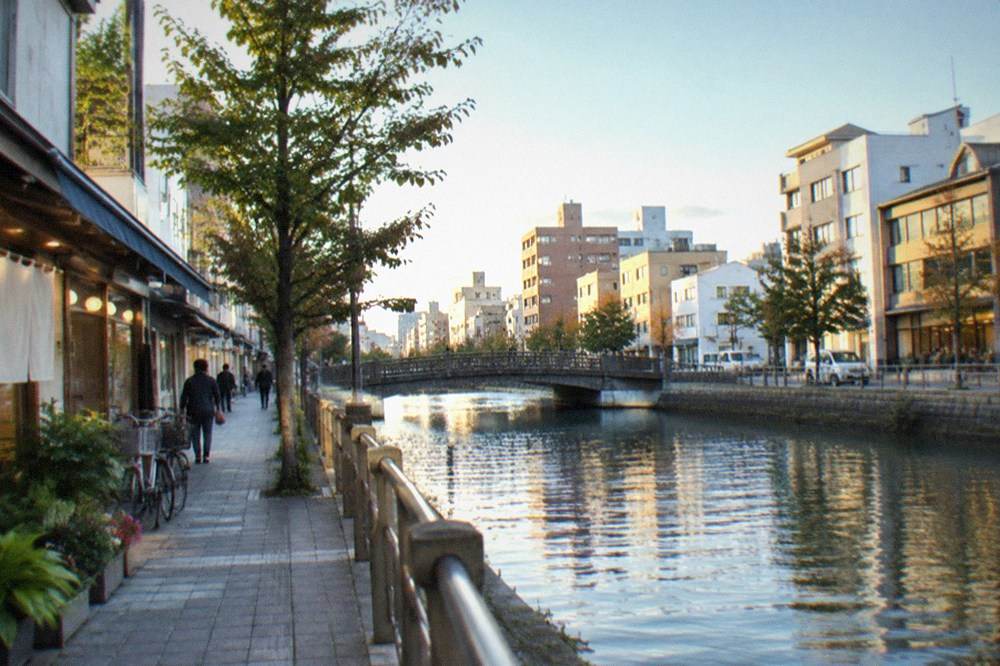 A shopping complex interior with a canal running between lit storefronts at night