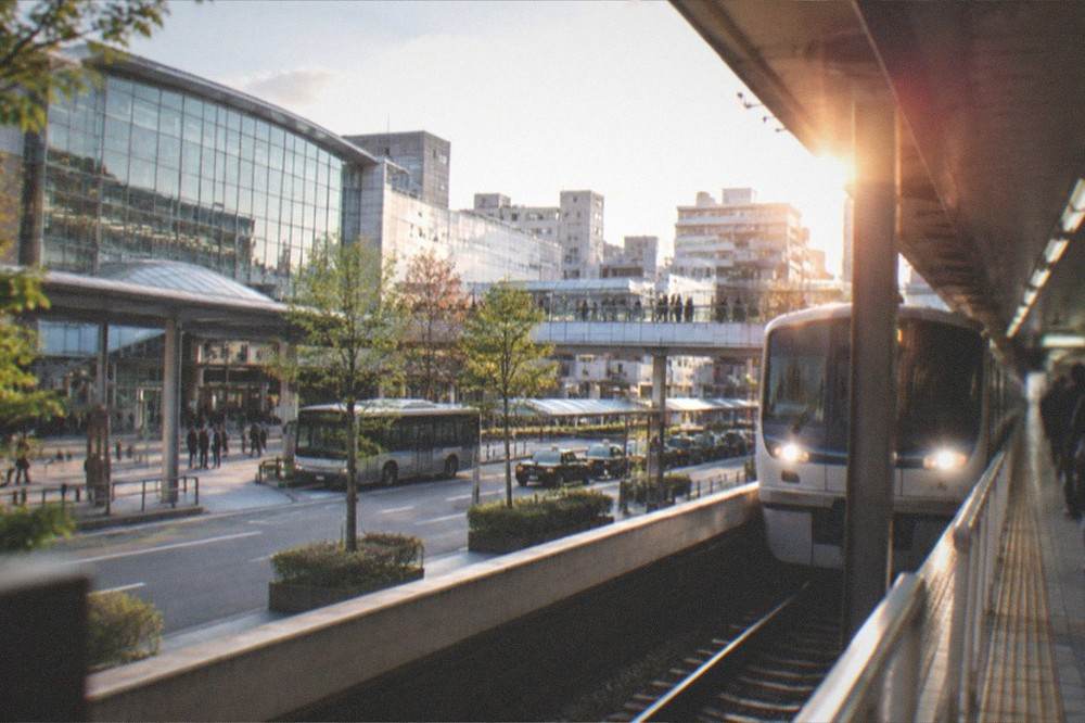 A subway platform in Fukuoka with a clean modern train arriving and platform signs overhead
