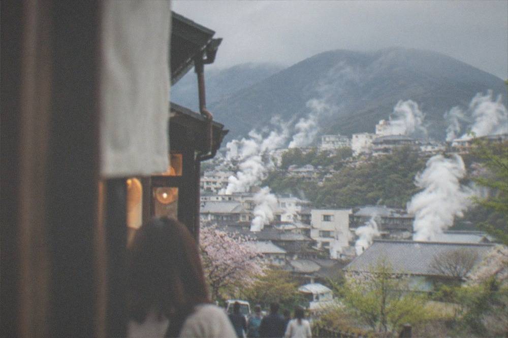Steam rising from hot spring vents across a hillside town in Beppu
