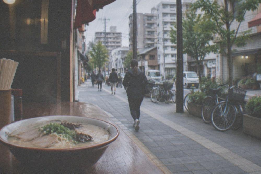 A steaming bowl of tonkotsu ramen on a wooden counter beside chopsticks